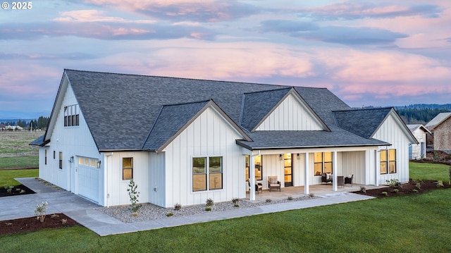 back of house with a lawn, board and batten siding, and a shingled roof