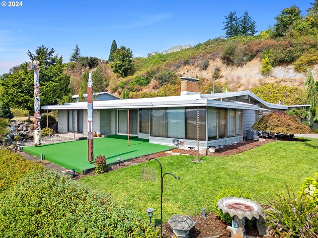 back of property with a mountain view, a lawn, a sunroom, and cooling unit