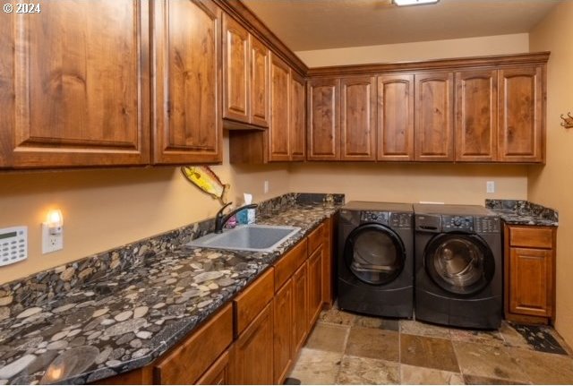 washroom with sink, washing machine and clothes dryer, and cabinets