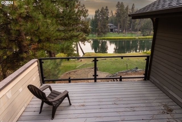 deck at dusk featuring a water view