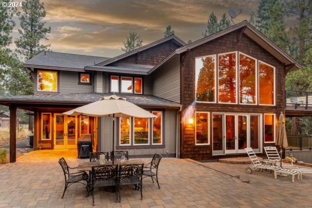 back house at dusk featuring a patio