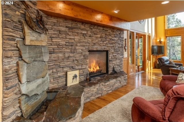 living room with beamed ceiling, a fireplace, and light wood-type flooring