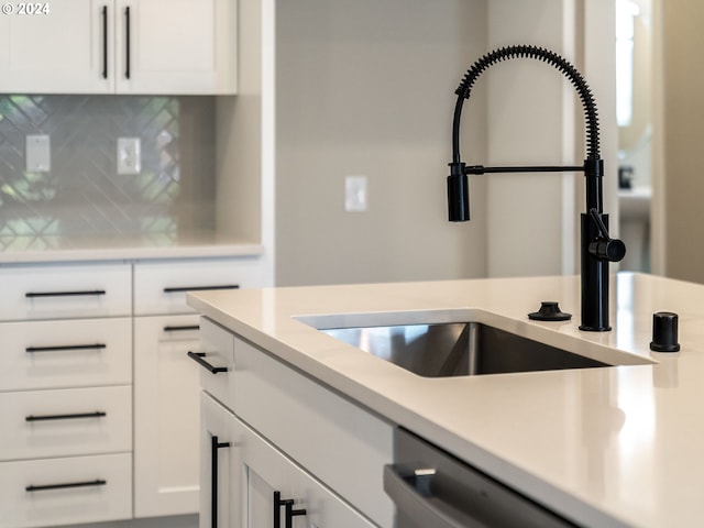 kitchen with a sink, tasteful backsplash, white cabinetry, light countertops, and dishwasher