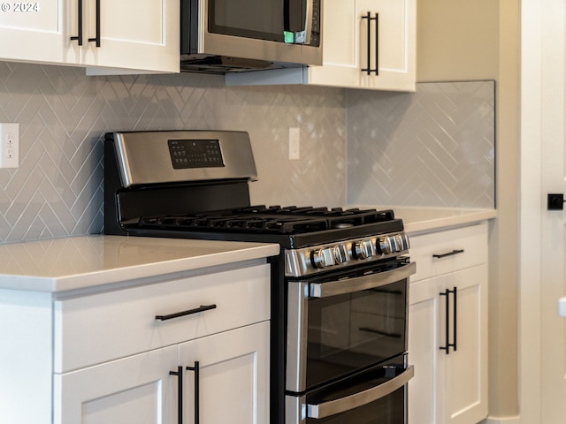 kitchen with stainless steel appliances, backsplash, and white cabinets