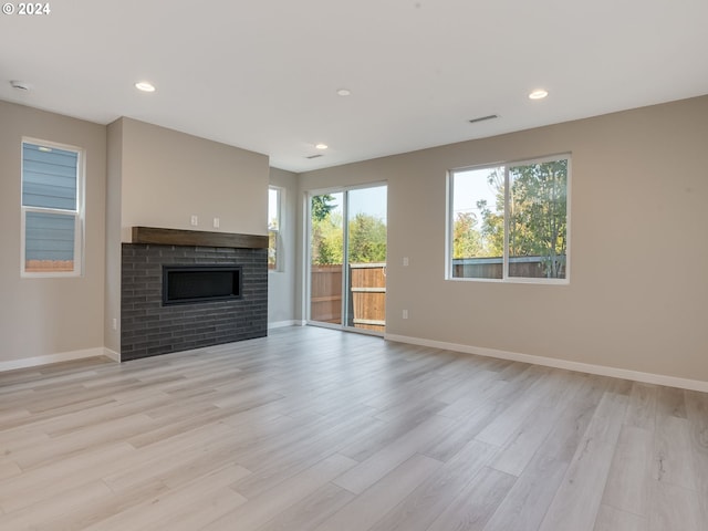 unfurnished living room featuring light wood-type flooring, baseboards, and a fireplace