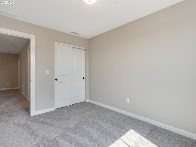 unfurnished bedroom with a closet, visible vents, baseboards, and carpet