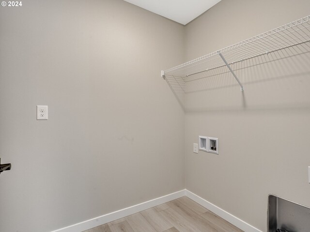 clothes washing area featuring baseboards, washer hookup, laundry area, and light wood finished floors