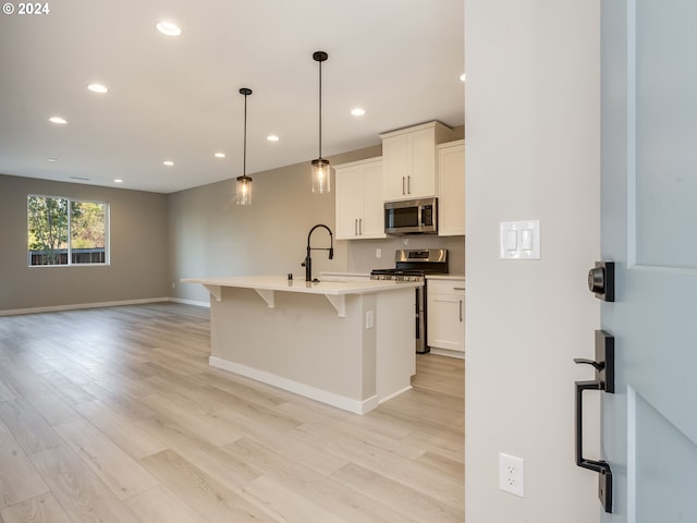 kitchen featuring light wood finished floors, a sink, a kitchen breakfast bar, stainless steel appliances, and light countertops