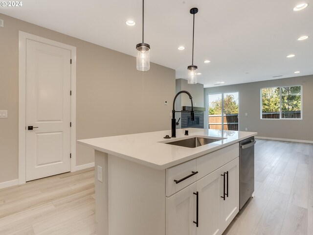 kitchen featuring light hardwood / wood-style floors, hanging light fixtures, a center island with sink, and sink