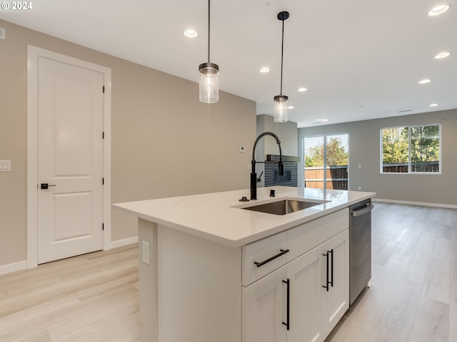 kitchen with a sink, pendant lighting, open floor plan, and light wood finished floors