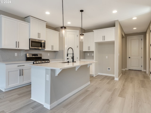 kitchen featuring a center island with sink, light hardwood / wood-style floors, stainless steel appliances, sink, and white cabinetry