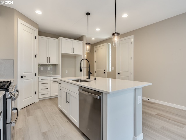 kitchen with light wood-type flooring, decorative backsplash, appliances with stainless steel finishes, white cabinetry, and a sink