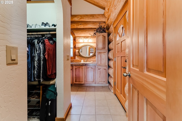 bathroom featuring vanity, vaulted ceiling, log walls, and tile patterned floors