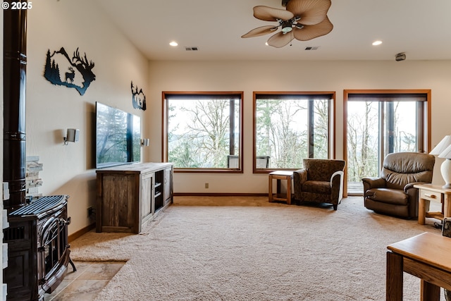 living room with light carpet, ceiling fan, and a wood stove