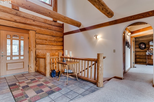 foyer entrance featuring a healthy amount of sunlight, beam ceiling, light colored carpet, and log walls