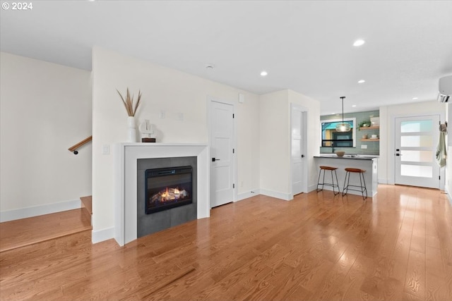 unfurnished living room featuring light hardwood / wood-style floors and an AC wall unit