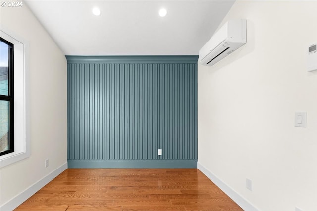 empty room featuring light wood-type flooring and an AC wall unit