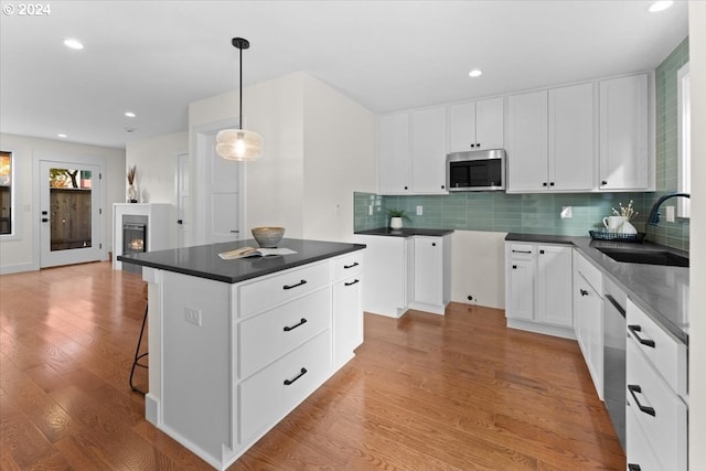 kitchen with pendant lighting, sink, white cabinets, a center island, and stainless steel appliances