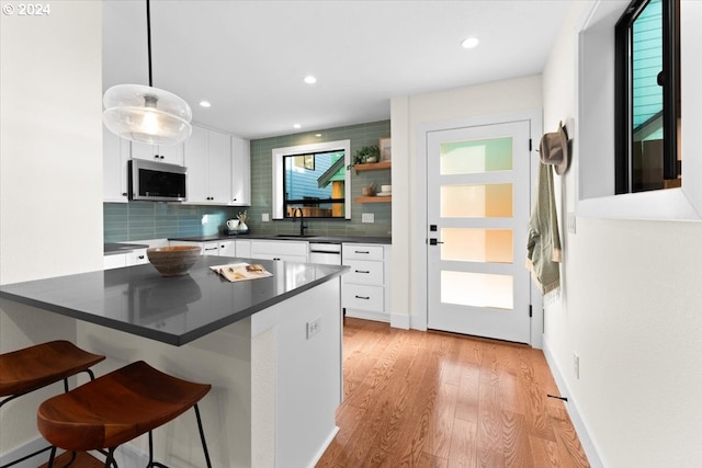 kitchen with white cabinetry, decorative light fixtures, stainless steel appliances, and a breakfast bar