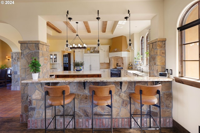 4974 W 44th Ave, Eugene, OR 97405 - kitchen featuring high end stove, premium range hood, arched walkways, white cabinets, and hanging light fixtures