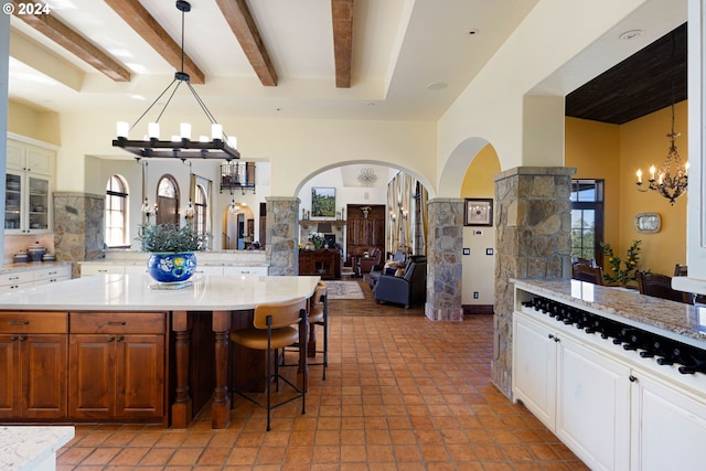 4974 W 44th Ave, Eugene, OR 97405 - kitchen featuring a chandelier, arched walkways, open floor plan, a breakfast bar, and beamed ceiling