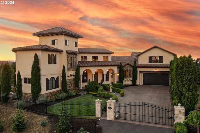 mediterranean / spanish house featuring a porch, decorative driveway, a fenced front yard, and a gate