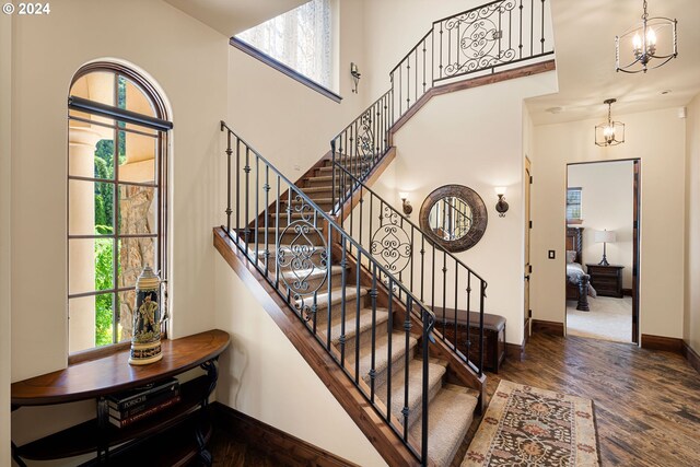 4974 W 44th Ave, Eugene, OR 97405 - staircase with wood finished floors, baseboards, a towering ceiling, and a chandelier