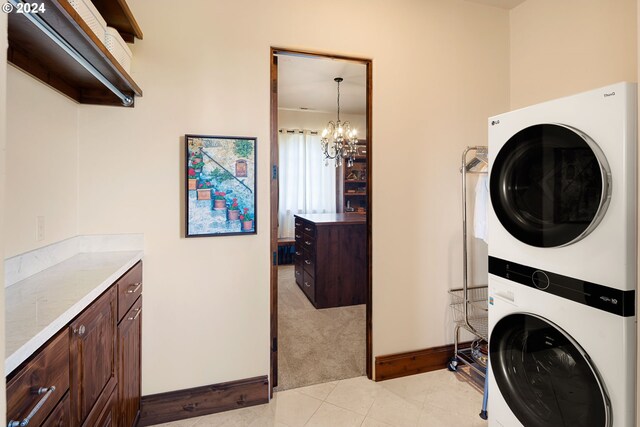 4974 W 44th Ave, Eugene, OR 97405 - laundry area with stacked washer / dryer, a chandelier, cabinet space, light carpet, and light tile patterned floors