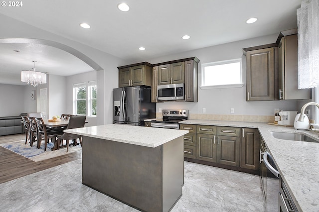 kitchen with appliances with stainless steel finishes, dark brown cabinets, sink, a chandelier, and hanging light fixtures