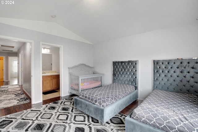 bedroom with ensuite bathroom, lofted ceiling, and dark wood-type flooring