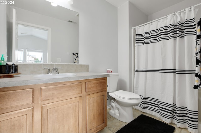 bathroom with tile patterned flooring, vanity, toilet, and lofted ceiling