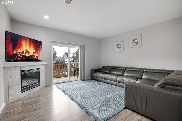 living room featuring light wood-type flooring and a tile fireplace