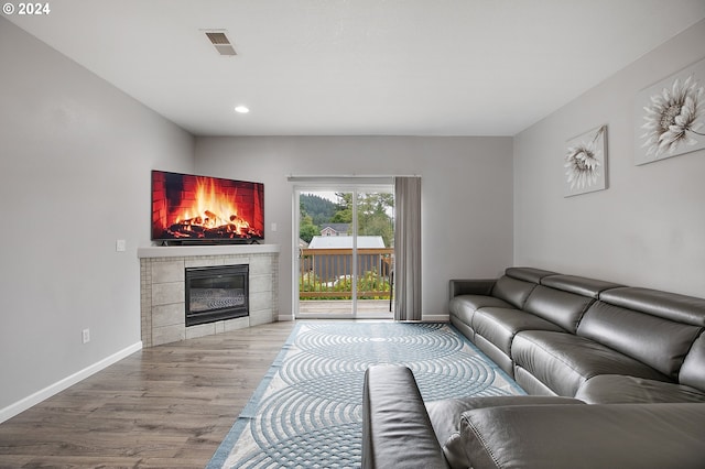 living room featuring light hardwood / wood-style flooring and a tiled fireplace