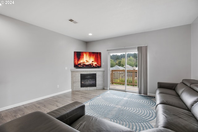 living room with a tiled fireplace and hardwood / wood-style flooring