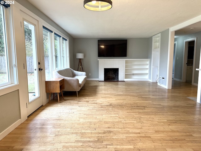 unfurnished room with a fireplace, light hardwood / wood-style flooring, and a healthy amount of sunlight