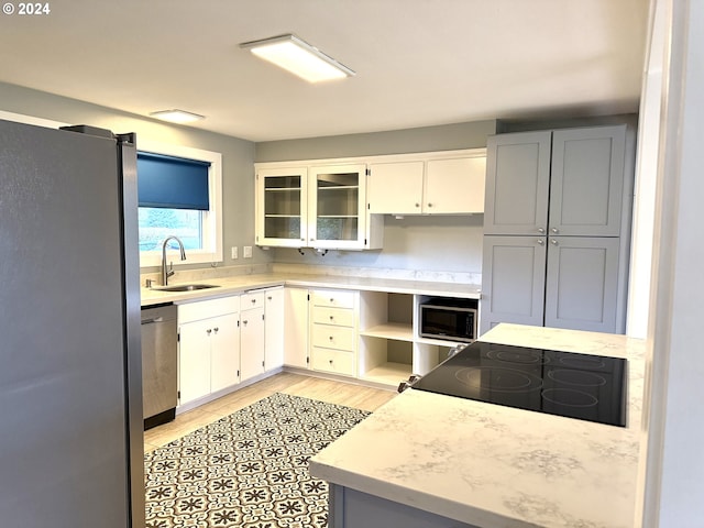 kitchen featuring sink, white cabinets, stainless steel appliances, and light wood-type flooring