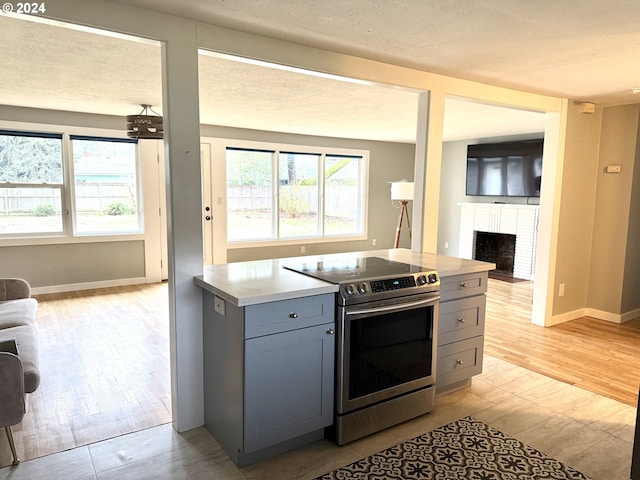 2936 Willakenzie Rd, Eugene, OR 97401 - kitchen featuring stainless steel range with electric cooktop, open floor plan, gray cabinets, light wood-style flooring, and a textured ceiling