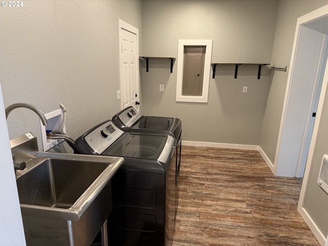 clothes washing area with electric panel, separate washer and dryer, dark hardwood / wood-style floors, and sink