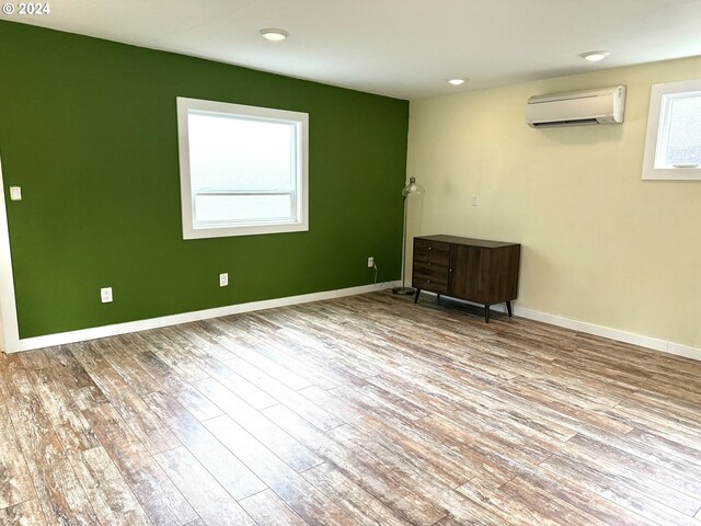 unfurnished room with light wood-type flooring and a wall mounted AC