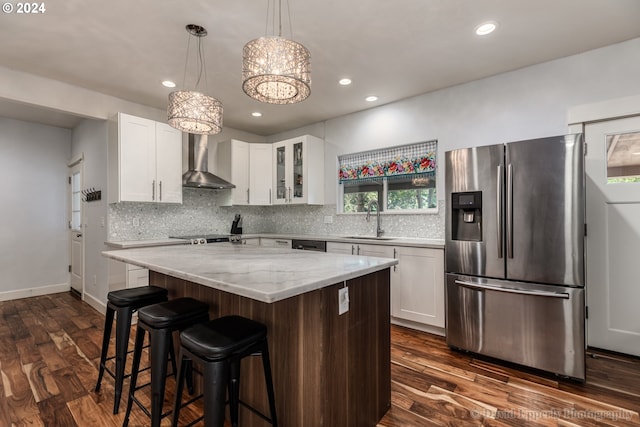 kitchen featuring a center island, white cabinetry, wall chimney range hood, stainless steel fridge, and dark wood-type flooring