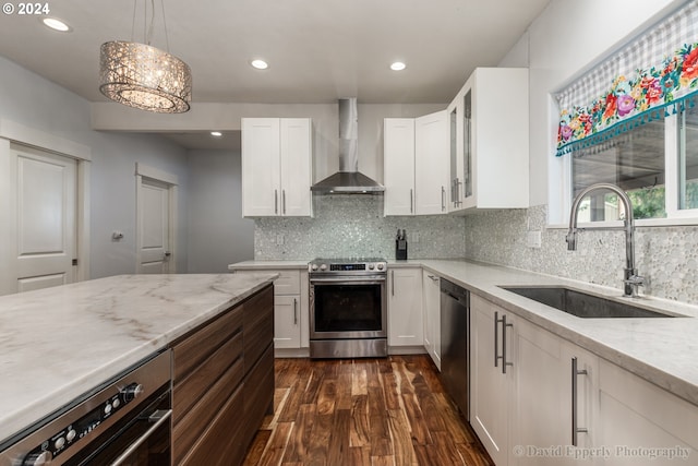 kitchen featuring dark hardwood / wood-style floors, wall chimney exhaust hood, stainless steel appliances, sink, and white cabinets