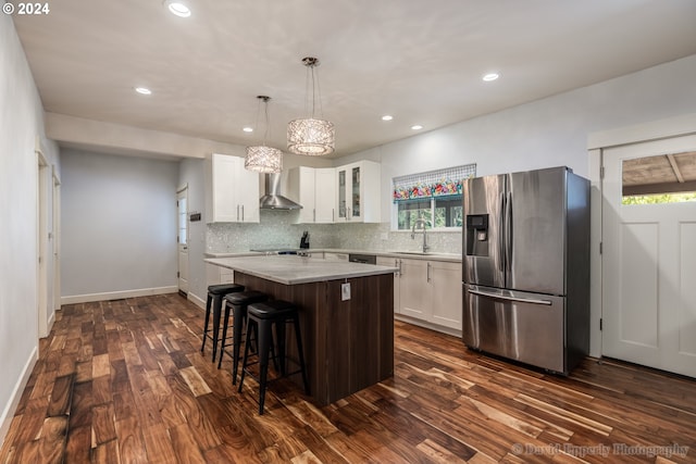 kitchen featuring stainless steel fridge with ice dispenser, wall chimney exhaust hood, plenty of natural light, and a center island