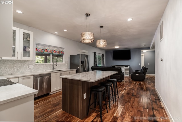 kitchen featuring white cabinets, hanging light fixtures, appliances with stainless steel finishes, sink, and a kitchen island