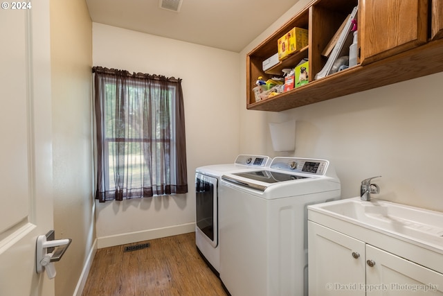 laundry area featuring sink, washing machine and clothes dryer, cabinets, and light hardwood / wood-style flooring