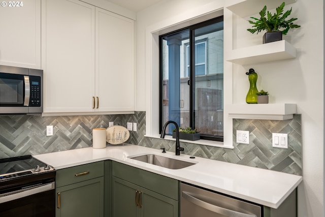 kitchen with stainless steel appliances, white cabinetry, sink, and green cabinetry