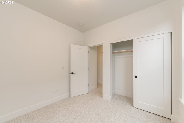 unfurnished bedroom with ensuite bathroom, light carpet, and a closet