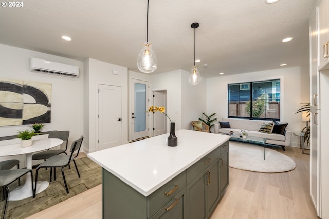 kitchen with a wall mounted AC, a textured ceiling, a kitchen island, light wood-type flooring, and decorative light fixtures