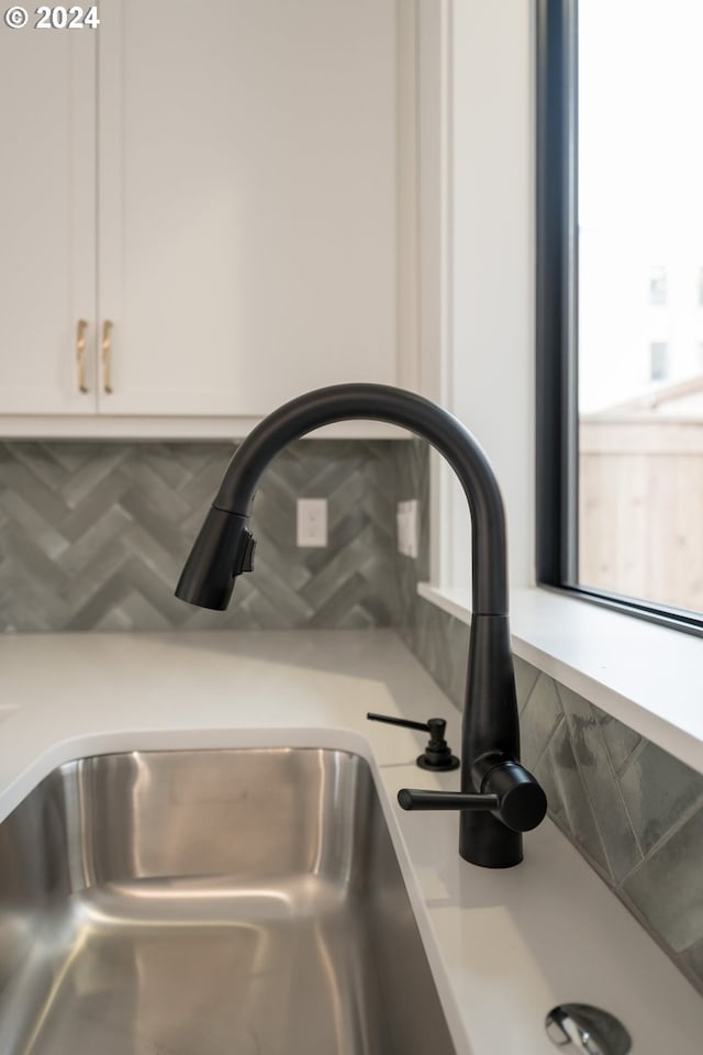 room details with white cabinets, decorative backsplash, and sink