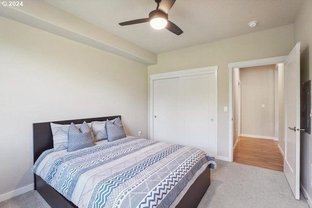 bedroom with ceiling fan, a closet, and light carpet