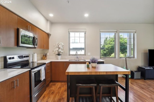 kitchen with a center island, a kitchen breakfast bar, sink, light wood-type flooring, and appliances with stainless steel finishes